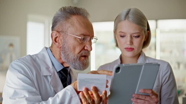 Pharmacy consultants looking tab computer examining tablets in drugstore closeup