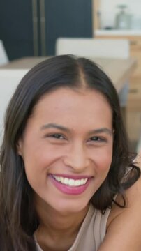Vertical video: Camera starting, woman in beige tank top posing for portraits on couch