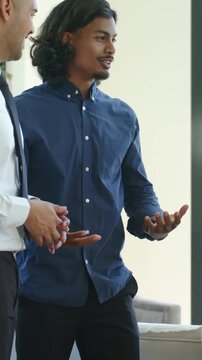 Vertical video: After cue, navy-shirt man explaining to group in lounge, listener in tie