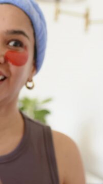 Vertical video: Cam focusing, woman in blue band and tank showing red patch for skincare at home