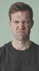 Fototapeta premium A man is experiencing a toothache, he presses his right hand against his cheek and grimaces in discomfort, vertical