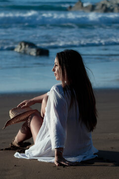 Woman relaxing on beach watching ocean waves