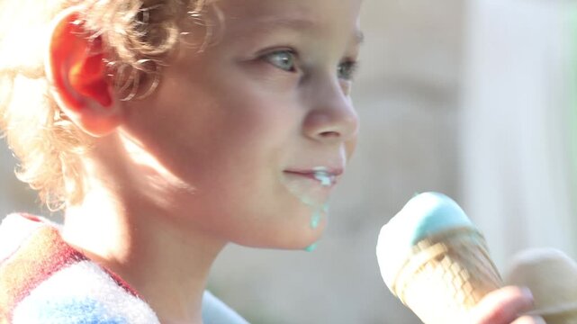 A little boy licking two ice creams