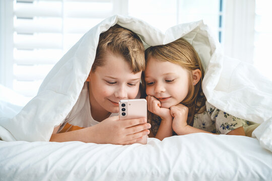 Leisure concept. Happy children listening to music or chatting on her smartphone