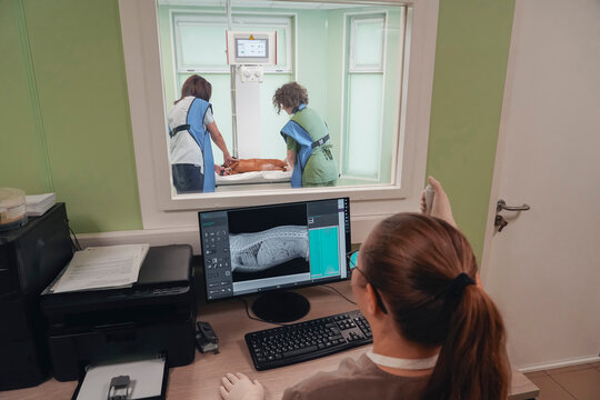 Vets X-ray a dog in clinic. A pro monitors live results on a computer screen from the control room