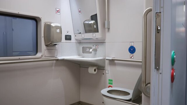 Accessible toilet interior in a passenger train carriage with sink and mirror. Public restroom facilities for disabled travelers on railway transit. Clean washroom inside rail car cabin.