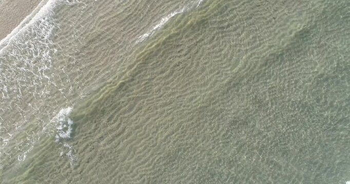 Rhythmic waves washing onto a sandy beach from above The Concept of peace and relaxation