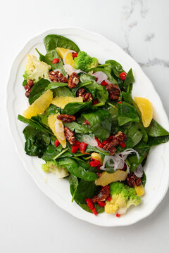 Fresh mixed green salad with avocado, red onion, pomegranate seeds and lemon on white background
