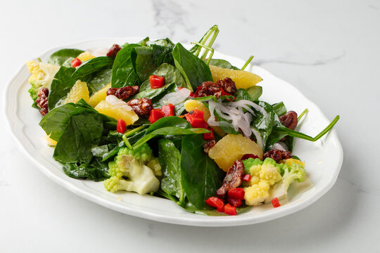 Fresh spinach salad with pineapple, red onion and pomegranate seeds on white background