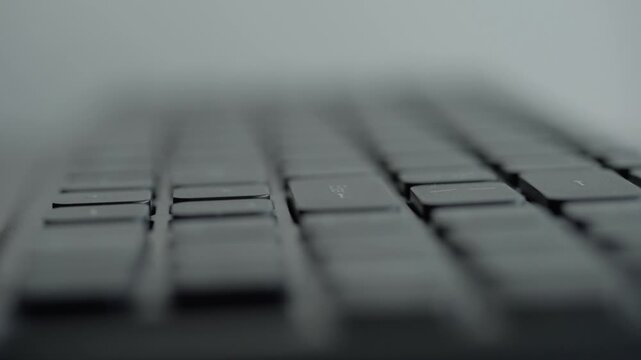 Hands focused typing on illuminated keyboard, shallow depth of field shows fingertip rhythm on keys with soft blue glow, steady pace and quiet office vibe, remote work or coder