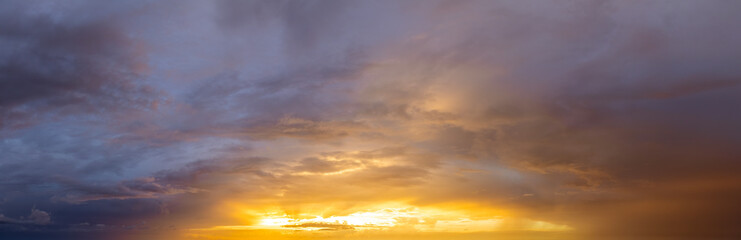 Fototapeta premium Dramatic sunset sky covered with colorful yellow clouds. Panoramic skyscape