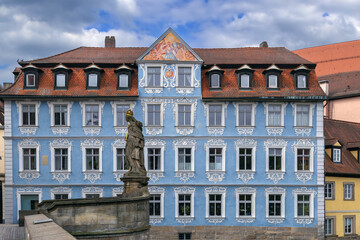 Fototapeta premium Blue baroque house on the river bank in Bamberg, Germany. View from Untere Brucke with Statue of St. Cunigunde