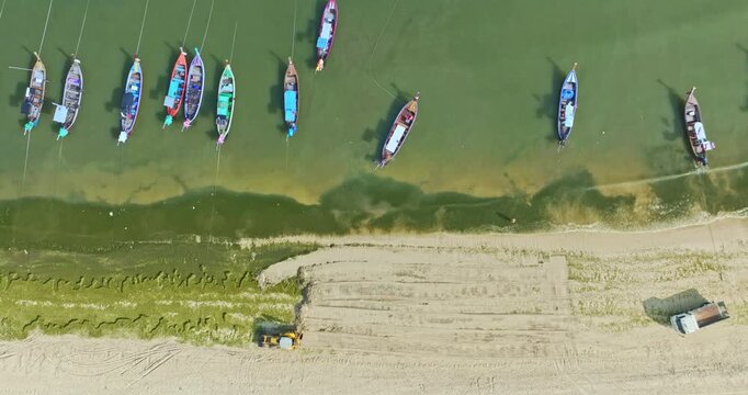 Aerial top down view of green algae spreading across the sandy shoreline of Patong Beach, Phuket. with a tractor actively cleaning the coast. The environmental maintenance, coastal ecosystem changes