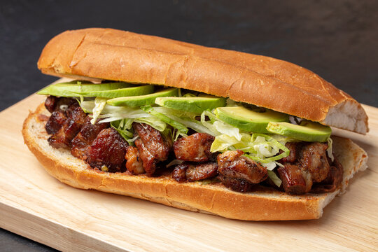 Grilled meat sandwich with lettuce and onions in a long bread roll
