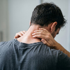 Fototapeta premium Close-up of a man with neck and back muscle pain - conceptual image of spinal injury, strain and inflammation on light background