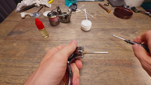 Wide Angle Macro Shot of Tightening Handle Shaft Nut of Spinning Fishing Reel During Internal Mechanism Assembly and Maintenance Repair Service