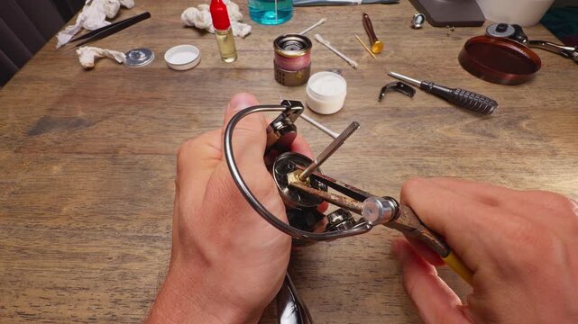 Close Up Macro Shot of Installing Rotor Nut Lock Clip on Spinning Fishing Reel During Final Maintenance Repair and Precision Assembly of Rotor Mechanism