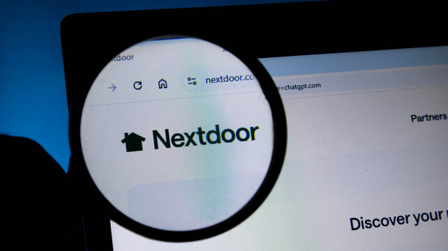 Closeup of a magnifying glass held over a computer screen showing the nextdoor website logo and url in the browser address bar