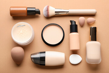 Naklejka premium Face powders, foundation, brush and sponges on beige background, flat lay
