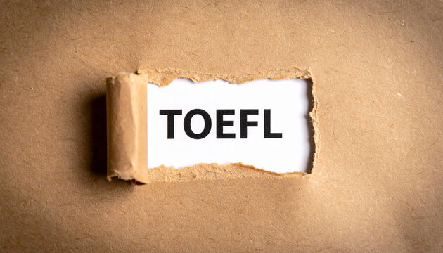 TOEFL exam preparation concept. Text on note paper with push pin and torn paper reveal. English as a foreign language test for international students, academic success, and study abroad goals.