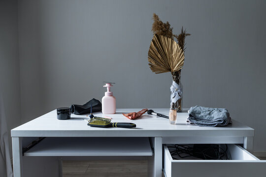 Makeup accessories and cosmetics arranged on a white desk