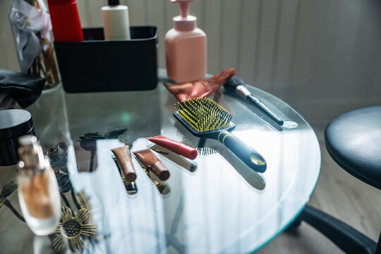 Makeup products and beauty tools on a glass table