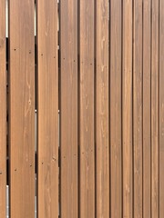 Fototapeta premium Vertical wooden slat fence with natural brown grain pattern and screws