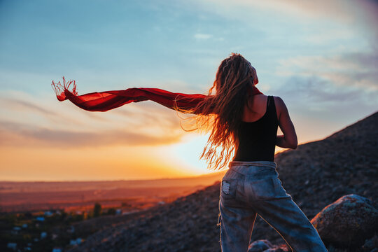 Woman with red scarf at sunset in mountains