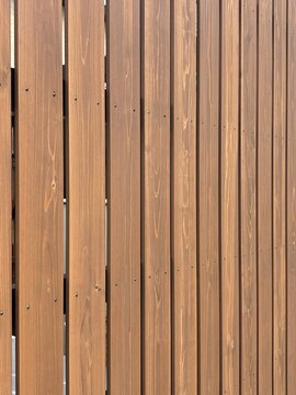 Vertical wooden slat fence with natural brown grain pattern and screws