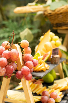Mesa de aperitivos con quesos variados y frutas frescas de temporada, vertical