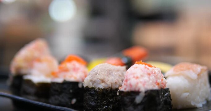 Cinematic close-up of assorted Japanese sushi pieces on a black tray, fresh nigiri and maki rolls, Asian cuisine and dining concept