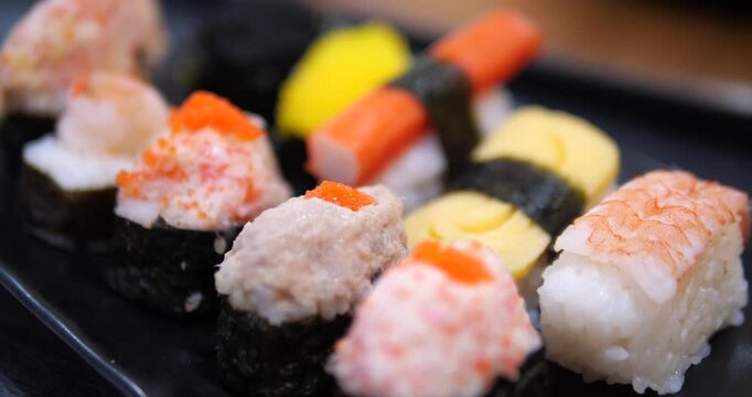 Cinematic close-up of assorted Japanese sushi pieces on a black tray, fresh nigiri and maki rolls, Asian cuisine and dining concept