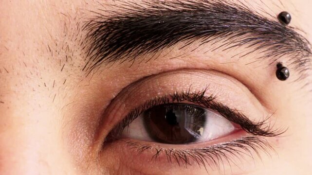 Eye, closeup and optometry with pupil for vision, eyebrow piercing and facial hair with retina. Person, lashes and ophthalmology with eyesight, visual care and stud in skin for body art with portrait