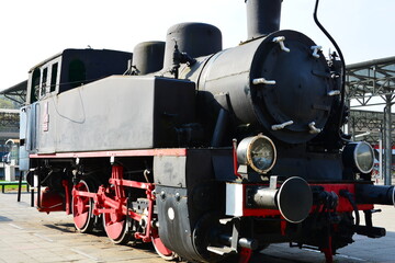 Vintage black steam locomotive with red wheels at a railway station © Wolf Steppe