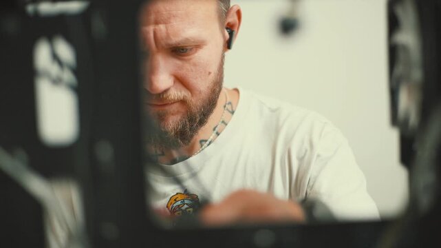 Man working on machine in a workshop during daytime near tools and equipment