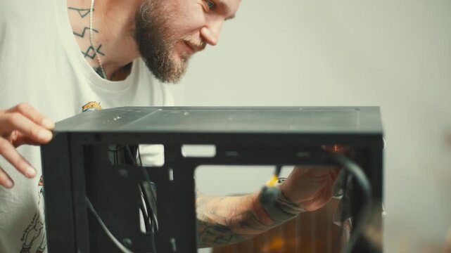 Man works on a computer case while cleaning and organizing wires in a simple indoor setting