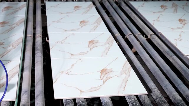 Ceramic tiles moving on conveyor rollers after printing process in industrial factory