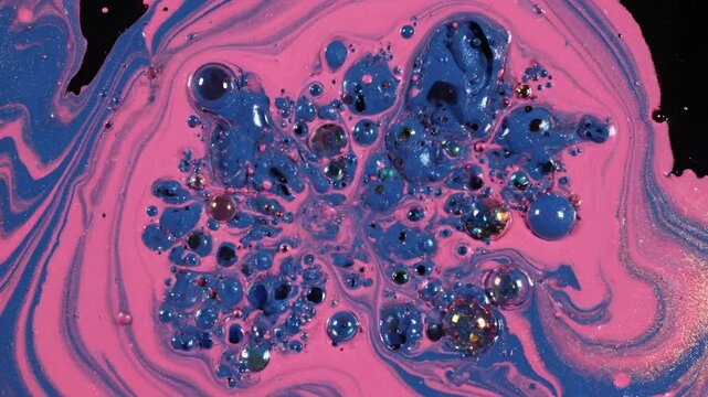Abstract macro shot of pink and blue liquid swirling with bubbles.