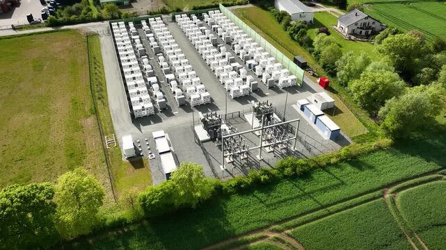 Aerial footage of industrial energy storage facility in industrial area. Battery energy storage system (BESS) instalation. Grid-scale battery storage and substation in  commercial and industrial area.