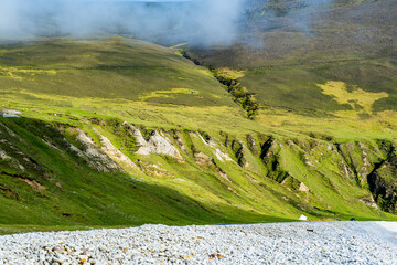 Obraz premium Southern Keel Beach on Achill Island, County Mayo, Ireland, with a pebble shore beneath dramatic sea cliffs. This image shows the rugged coastal edge of the beach from ground level.