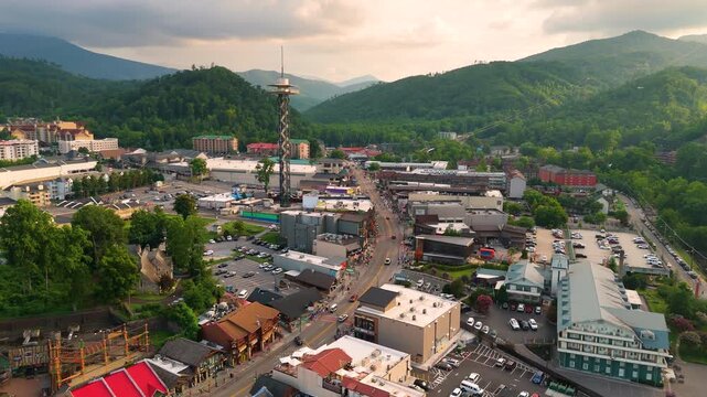 Aerial panorama of Gatlinburg, Tennessee with bustling main street filled with shops and attractions, observation tower and Smoky Mountains National Park nearby.