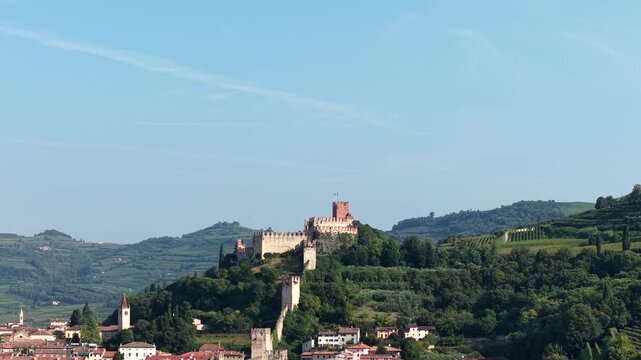 Drone flight near the ancient Scaliger Castle in Italy. Aerial view of the historical architecture and fortification in Soave under a clear blue summer sky.