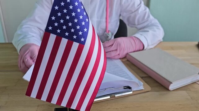 Person holding a document with a small American flag on a table during a focus task related to the USA concept