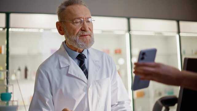 Elderly pharmacist smiling customer cashier closeup. Client showing smartphone