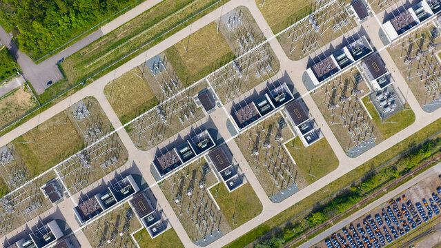 Aerial view of an electrical substation with high-voltage transformers and power grid infrastructure surrounded by green trees and a parking lot Velsen-Noord, North Holland, Netherlands.