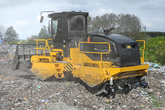 Heavy industrial machinery working at a large landfill site.  A view on a landfill compactor compacting and managing piles of waste.