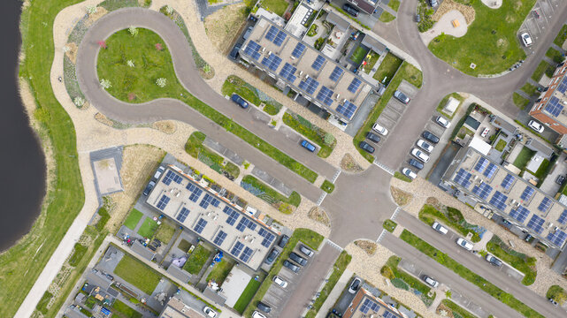 Aerial view of the modern Nobelhorst neighborhood featuring houses with solar panels on roofs, green gardens, and organized parking lots in Almere, Flevoland, Netherlands.