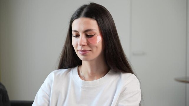 Close up of young woman applying hydrogel under eye patches during skincare routine at home. Beauty and self care concept with moisturizing eye masks, facial treatment, healthy glowing skin and