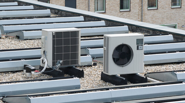 Aerial view of modern air conditioning units and heat pumps installed on a gravel rooftop in Almere, Flevoland, Netherlands.