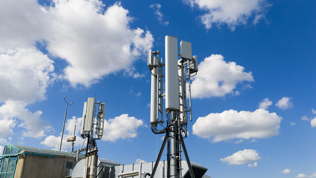 Aerial view of telecommunication antennas and cell towers on a rooftop under a bright blue sky with white clouds Amsterdam, North Holland, Netherlands.